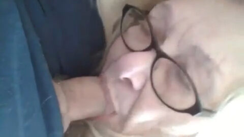Old mother wearing glasses on her knees giving a deep blowjob to her son in a taboo family scene