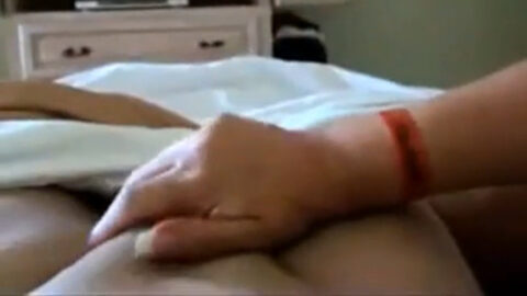 Amateur aunt stroking her real nephew's hard cock with her hand during taboo family handjob session at home.