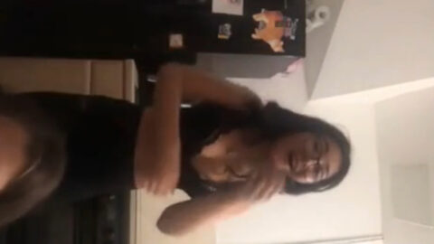 Two young women filming together indoors when one accidentally exposes her chest during a wardrobe malfunction while her friend reacts with shocked expression