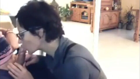 Mother kneeling between her son's legs giving him a blowjob while he plays video games in his gaming chair